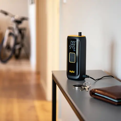 Mini compresseur électrique Aqila en charge sur une console d'entrée, prêt à l'emploi pour vélo.
